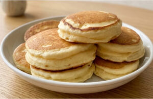 Przepis na wyjątkowo puszyste japońskie pancakes: Wysokie, delikatne i lekkie jak chmurka Puszyste japońskie pancakes na talerzu z syropem klonowym i owocami